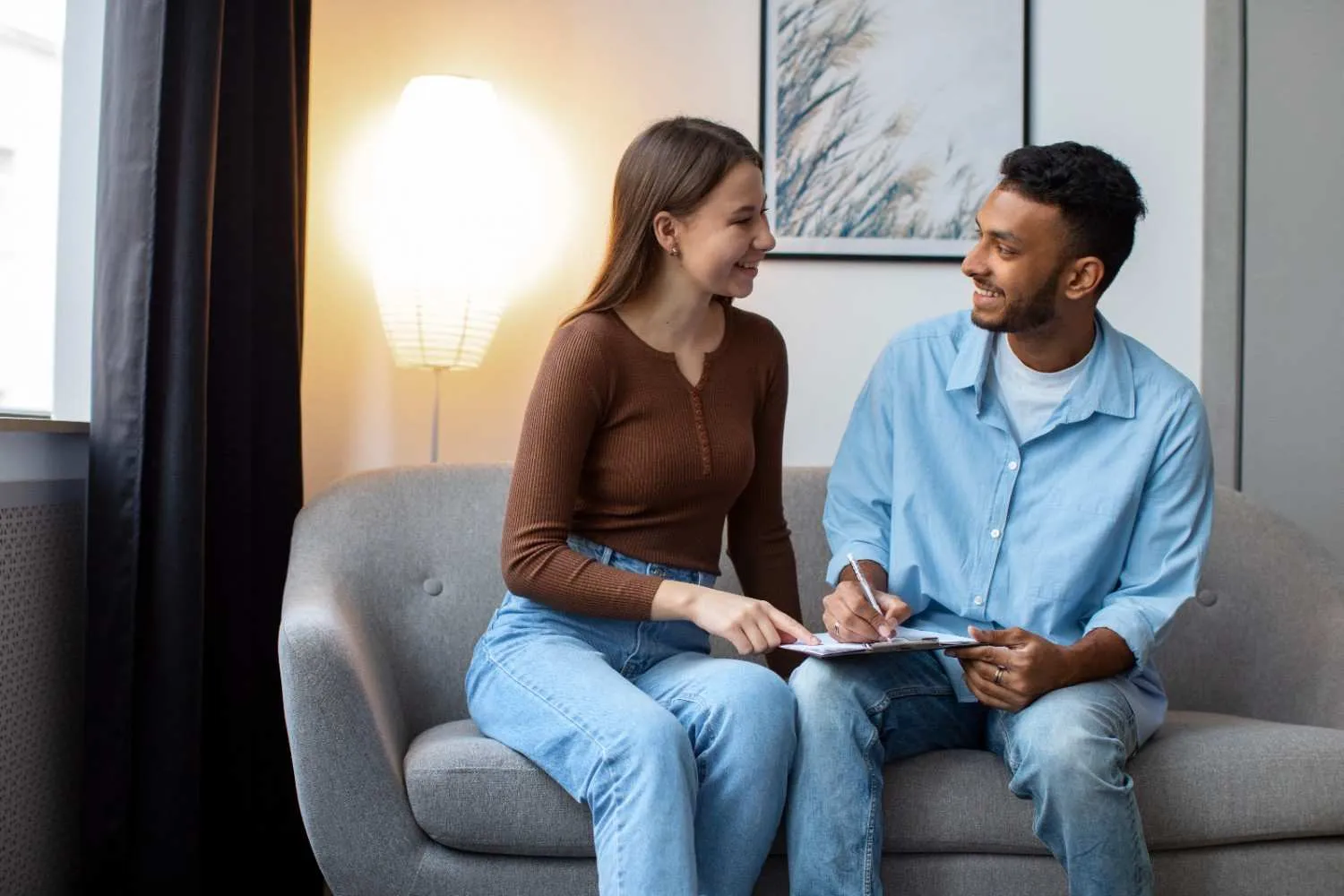 Two people talking on a sofa in a bright living room